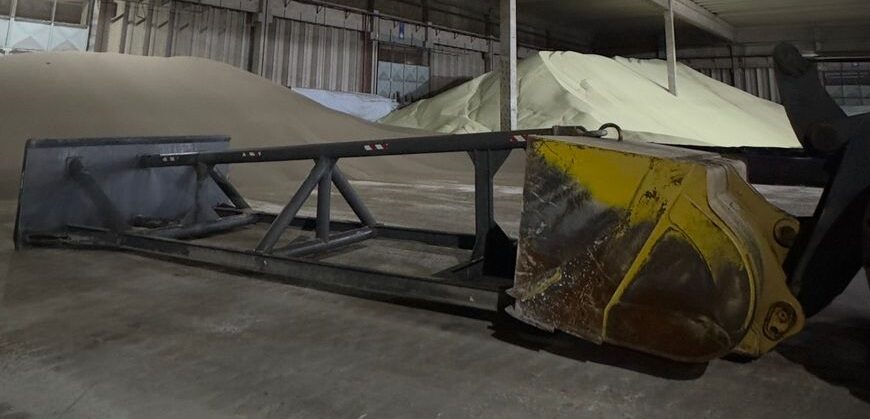 Implemento empurrador acoplado à concha de uma pá carregadeira John Deere 724