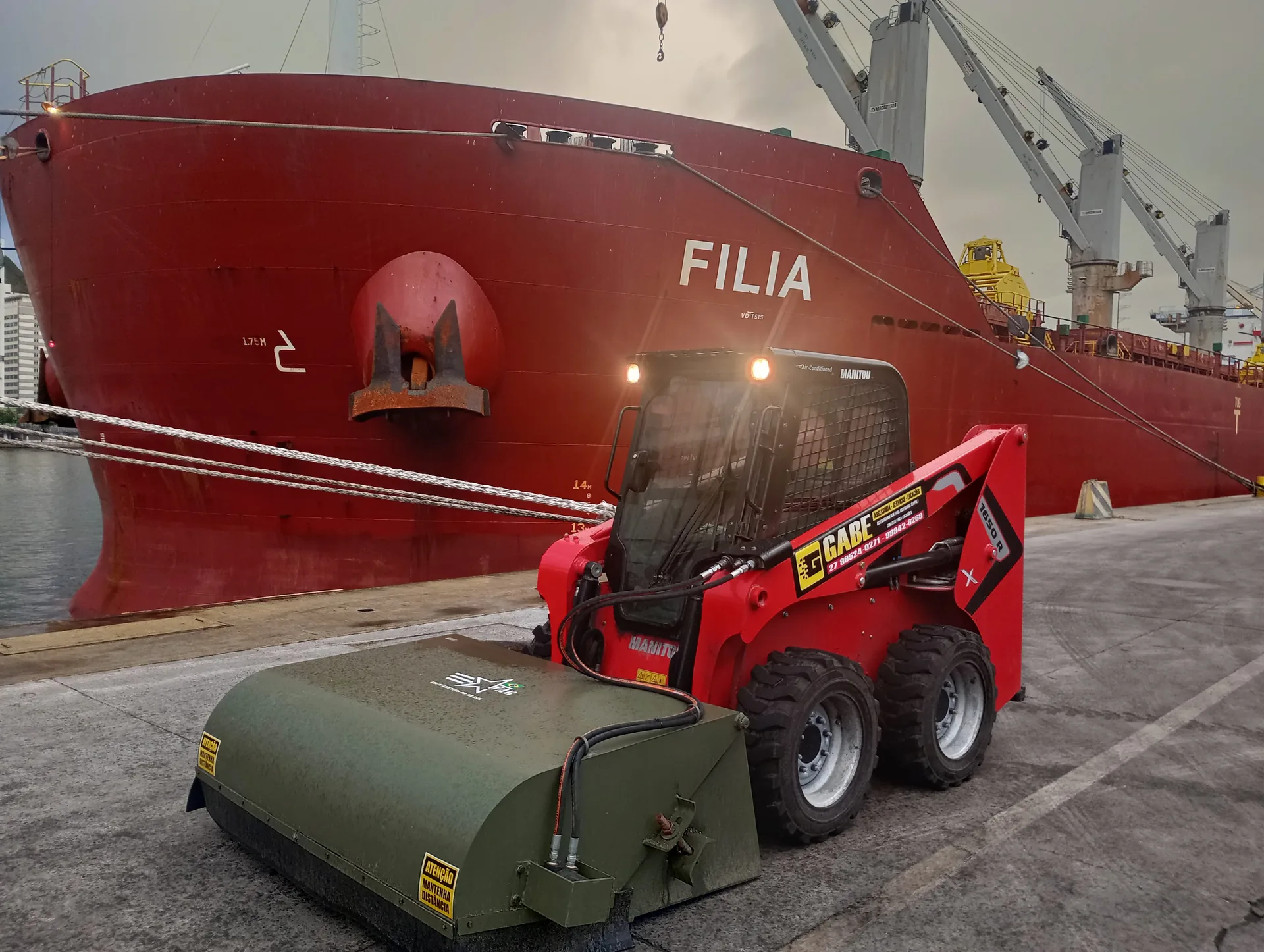Minicarregadeira Manitou 1650R com implemento varredeira em área portuária